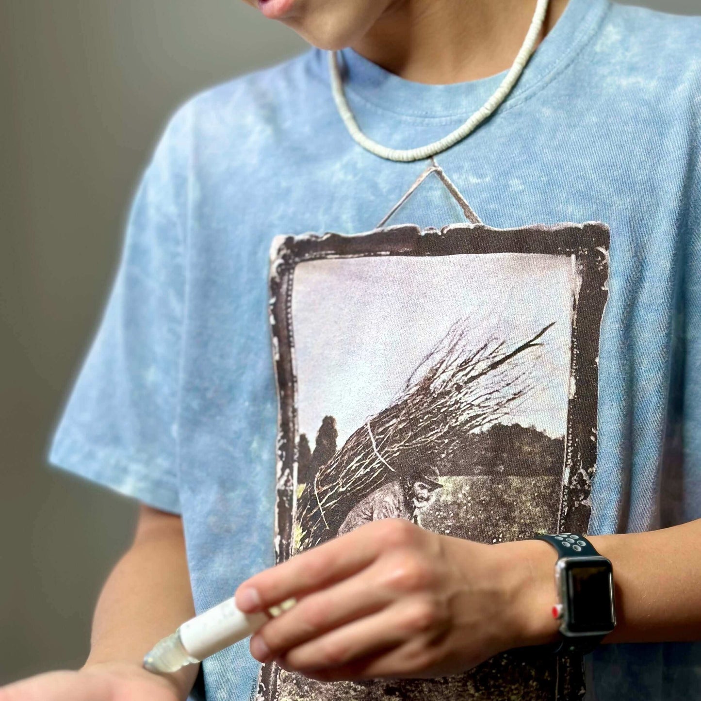 Guy with blue t-shirt using Roll-On Fragrance on his wrist.