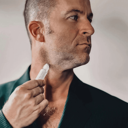 Man in black suit using Ode To a Gentleman Roll-On Perfume Oil Fragrance on his neck.