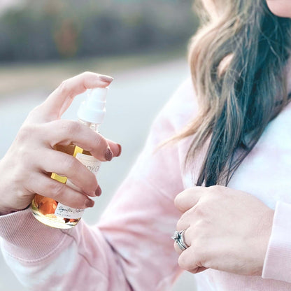 Woman using our Body Oil Serum on the ends of her hair.